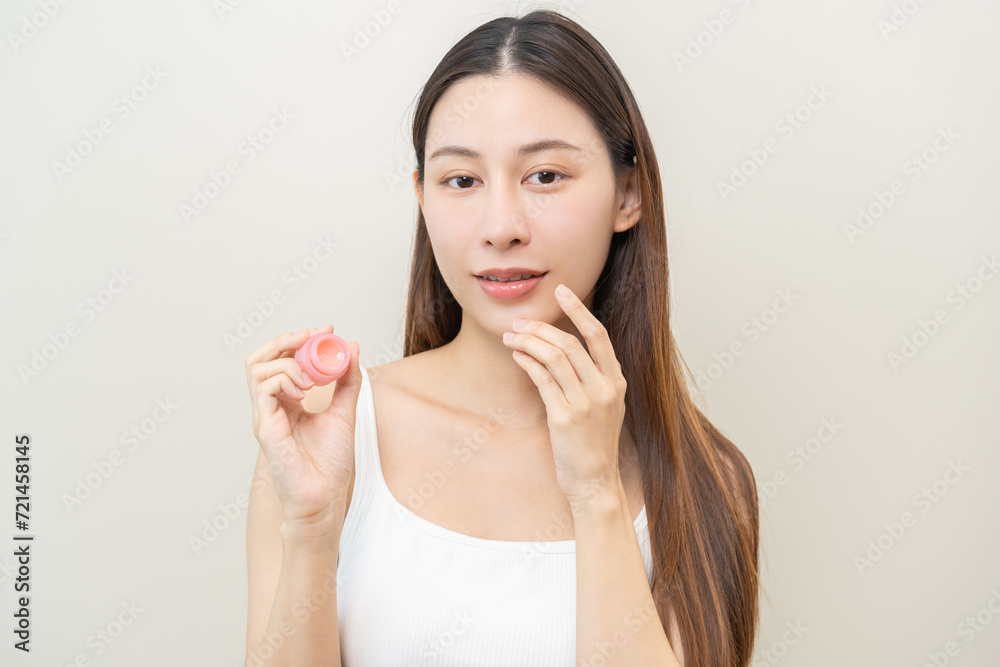 Lip care protection concept, asian young woman, girl applying balm from jar, taking with finger, touching on dry mouth from natural beauty product, skincare routine, makeup and cosmetics on background Lip care protection concept, asian young woman, girl applying balm from jar, taking with finger, touching on dry mouth from natural beauty product, skincare routine, makeup and cosmetics on background