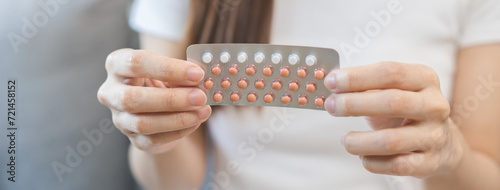 Contraception and pregnancy, menstruation concept, birth control pills asian young woman hand holding hormonal oral contraceptive medicine, take pharmaceutical to prevention, safe virus sex disease. photo