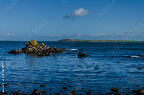 Gentle waves lapping the rocks at Co Down coast nearGroomsport with blue sky and sea and Copeland Island in the distance photo