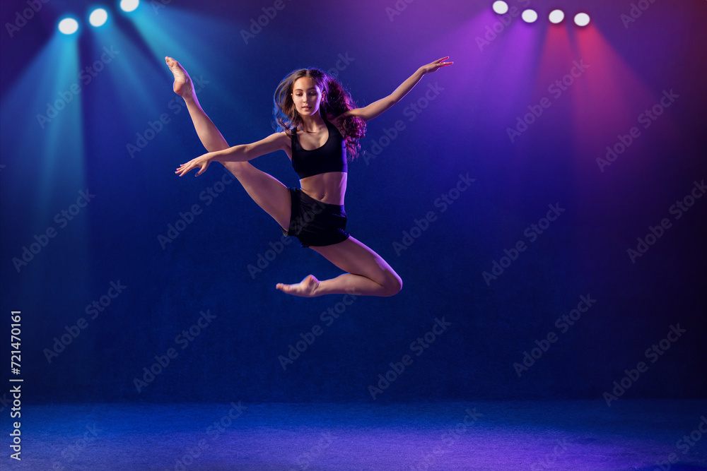 young performer of modern choreography dancing in the spotlights on a black background.