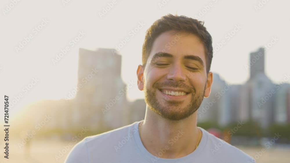 Handsome man looking at camera. Closeup positive guy smiling at camera. Portrait of male model posing on camera in urban sunset background. Cheerful man face with positive emotion
Handsome man looking at camera. Closeup positive guy smiling at camera. Portrait of male model posing on camera in urban sunset background. Cheerful man face with positive emotion