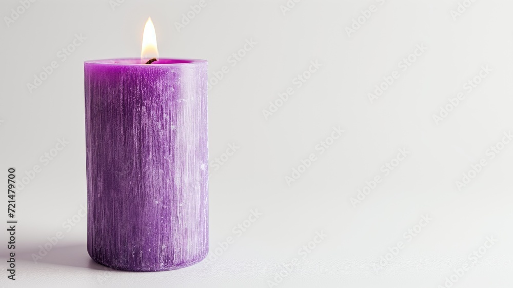 A single purple candle burning against a white backdrop A single purple candle burning against a white backdrop