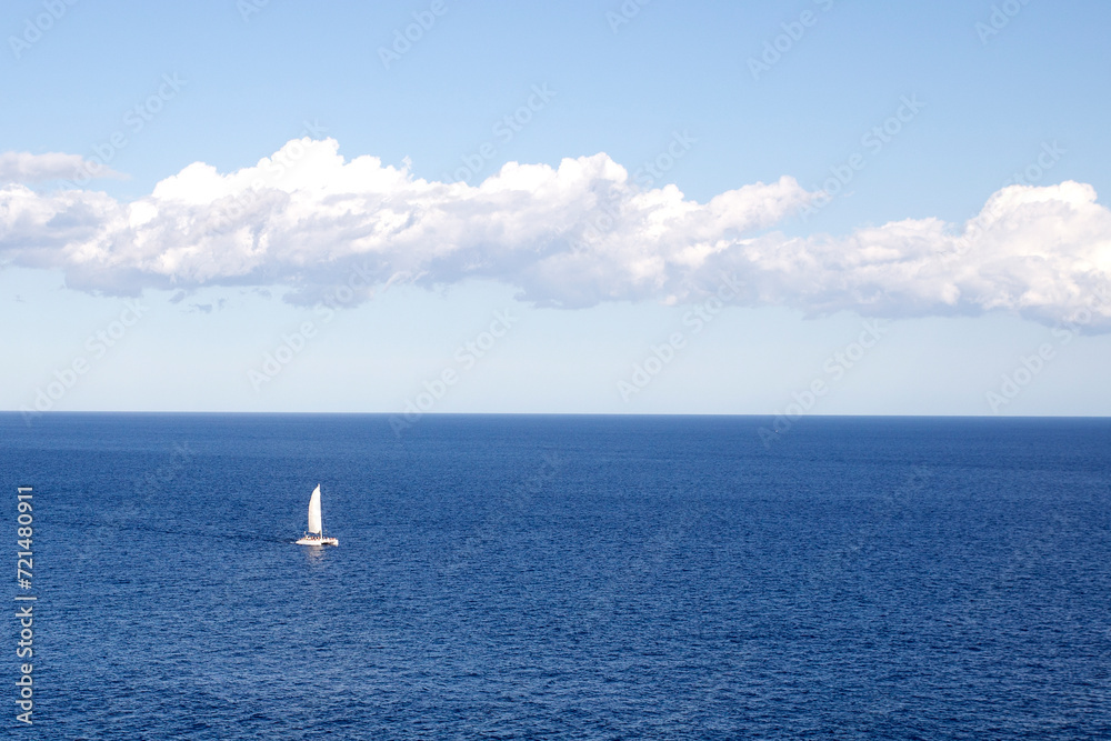 Sailboat sailing through the sea on the blue horizon