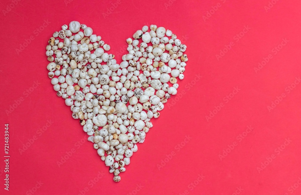Heart Shape Created with Fox Nut or Makhana on Red Background with Copy Space, Also Known as Lotus Seed Pop, Euryale Ferox or Gorgon Nut