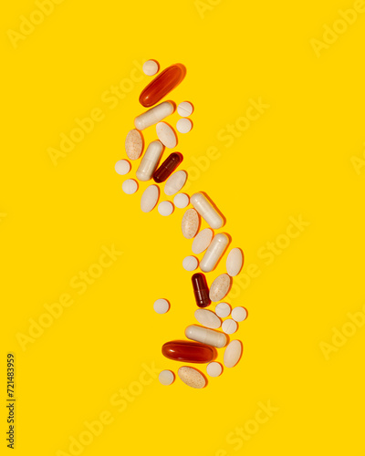 Various medication tablets and capsules on yellow background. Concept of healthcare and medicine. Top view, copy space