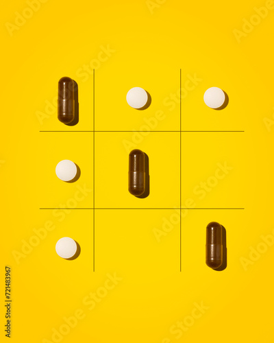 Creative photo of tablets on a yellow background. The tablets lie in the form of a tic-tac-toe game.