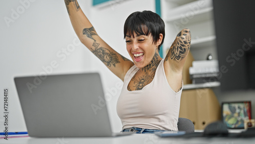 Hispanic woman with amputee arm business worker using laptop working with winner gesture at the office photo