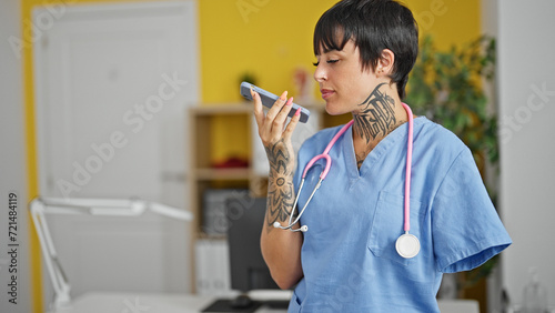 Hispanic woman with amputee arm doctor sending voice message by smartphone at clinic