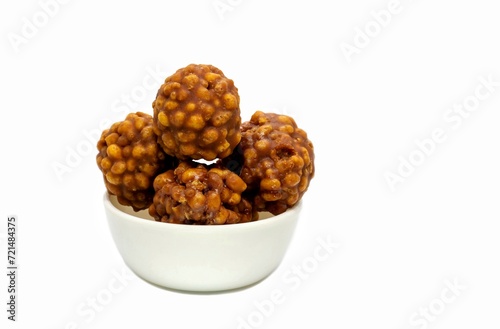 Jaggery Laddu or Gur Ladoo Indian Winter Sweets in a White Bowl Isolated on White Background with Copy Space