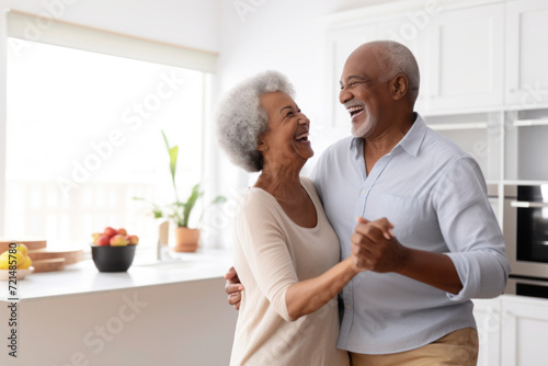 African multiracial married senior mature couple dancing in the kitchen