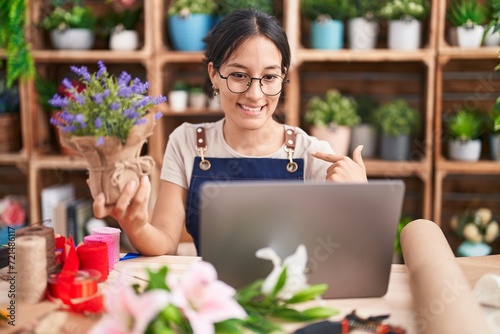Young hispanic woman working at florist shop doing video call looking confident with smile on face, pointing oneself with fingers proud and happy. © Krakenimages.com