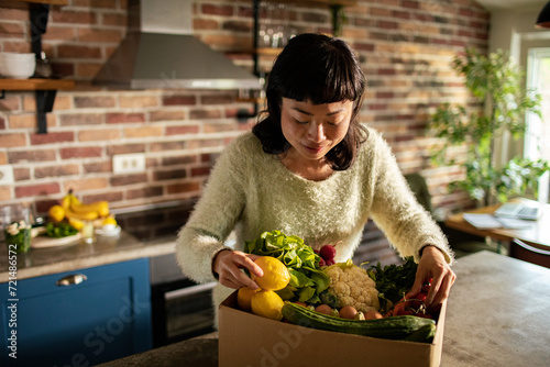 Japanese woman unpacking bought vegetables in home kitchen © Vorda Berge