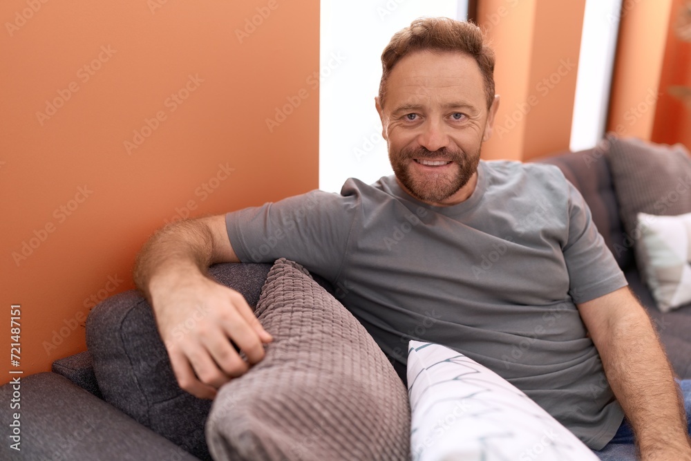 Middle age man smiling confident sitting on sofa at home Middle age man smiling confident sitting on sofa at home