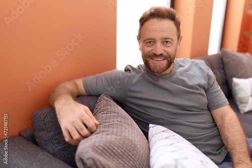 Middle age man smiling confident sitting on sofa at home