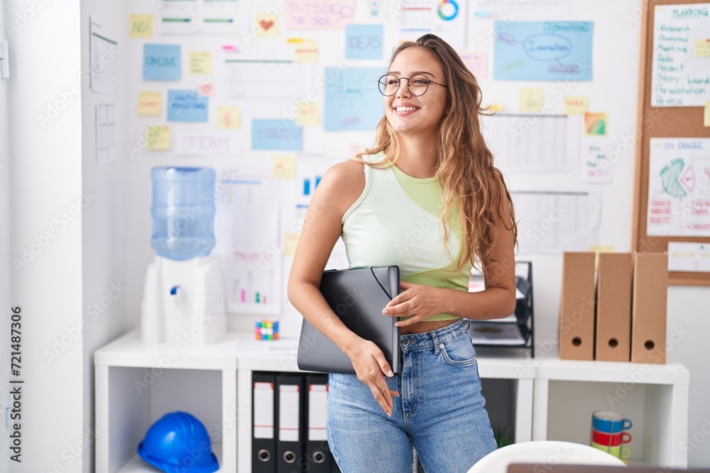 Young beautiful hispanic woman business worker smiling confident holding binder at office