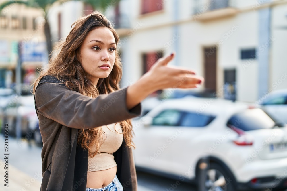 Young beautiful hispanic woman looking to the side with serious expression at street