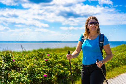 Nordic walking - beautiful woman exercising by the sea
