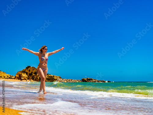 Beautiful woman walking on sunny beach Albufeira Algarve Portugal