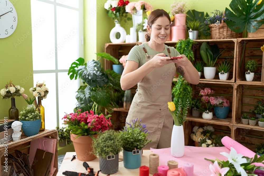 Young beautiful woman florist make photo to flower by smartphone at flower shop