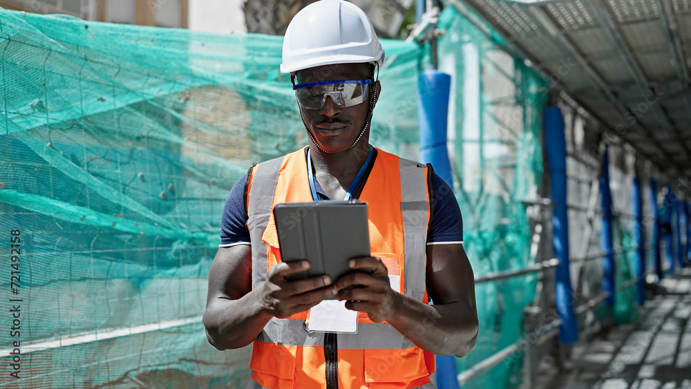 African american man builder using touchpad at construction place