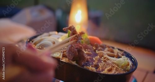 Murais de parede Close-up of a person enjoying a savory hot pot meal with chopsticks, with the wa