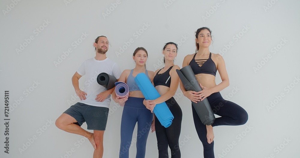 Obraz premium group of woman and man standing leaned on wall waiting for yoga class, before or after work out people in sportswear holds yoga mats looking happy and healthy, well-being, sports wellness concept