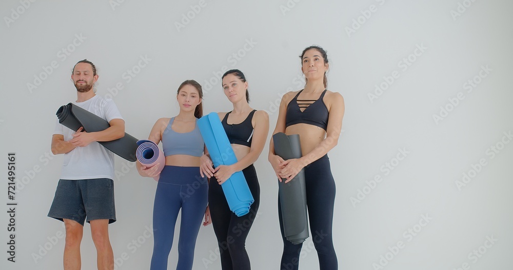 Obraz premium group of woman and man standing leaned on wall waiting for yoga class, before or after work out people in sportswear holds yoga mats looking happy and healthy, well-being, sports wellness concept