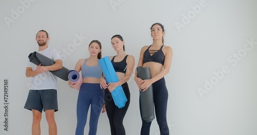 group of woman and man standing leaned on wall waiting for yoga class, before or after work out people in sportswear holds yoga mats looking happy and healthy, well-being, sports wellness concept