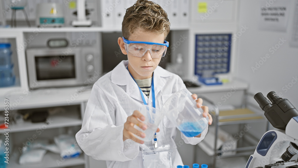 Adorable blond kid scientist seriously engaged in a chemistry experiment, pouring liquid into test tube while working in lab Adorable blond kid scientist seriously engaged in a chemistry experiment, pouring liquid into test tube while working in lab