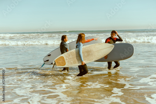Group of surfers with surfboards in wetsuit entering towards ocean for ride the waves