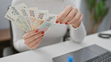 A young woman counts czech currency at her workplace, indicating finance, economy, or savings concepts in an office setting.