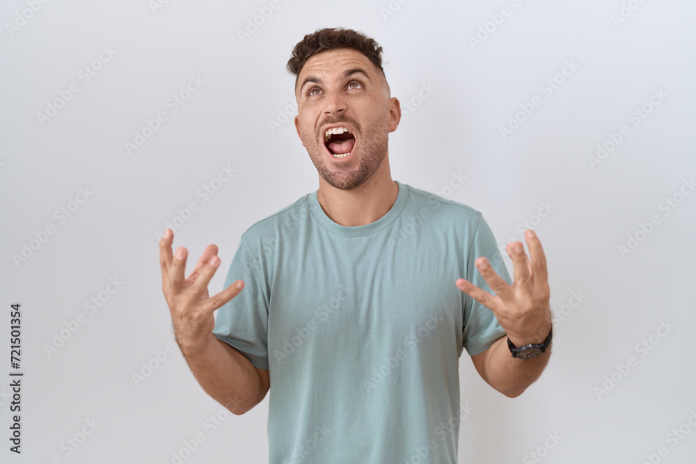 Hispanic man with beard standing over white background crazy and mad shouting and yelling with aggressive expression and arms raised. frustration concept. Hispanic man with beard standing over white background crazy and mad shouting and yelling with aggressive expression and arms raised. frustration concept.