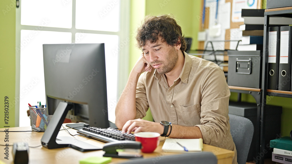 Young hispanic man business worker using computer tired at office
