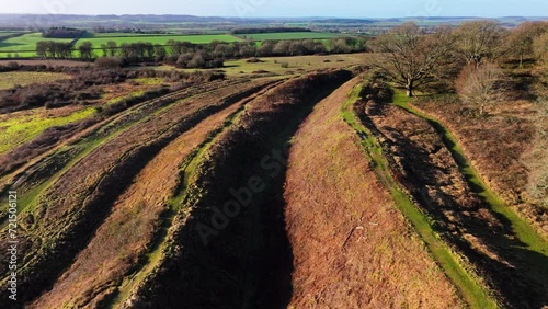 Aerial shot descending down towards ditches and ramparts of ancient hill fort at Bradbury rings, Dorset, UK photo