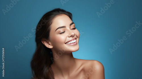 Portrait of a young woman with natural makeup and natural styling on blue background.