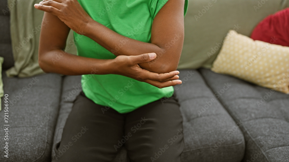 African american woman experiencing arm pain in a cozy living room setting