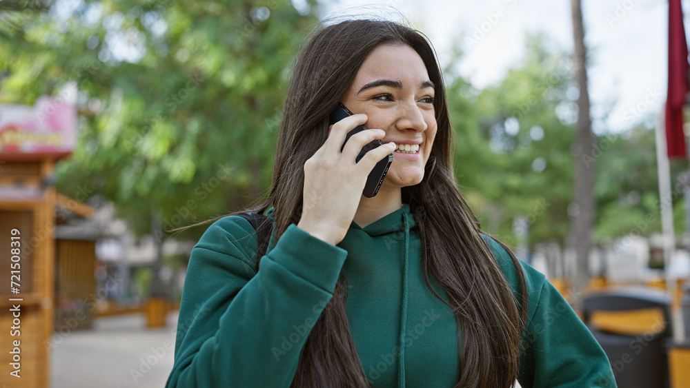 Smiling young woman using smartphone on a city street with trees in the background. Smiling young woman using smartphone on a city street with trees in the background.