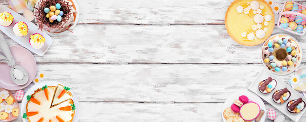 Easter or spring dessert food double border. Above view over a white wood banner background. Lemon tart, cupcakes, Easter egg and carrot cakes and a collection of sweets. Copy space.