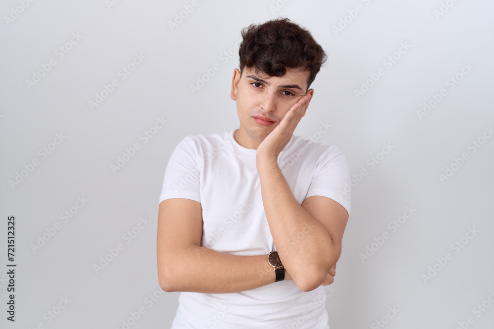 Young non binary man wearing casual white t shirt thinking looking tired and bored with depression problems with crossed arms. Young non binary man wearing casual white t shirt thinking looking tired and bored with depression problems with crossed arms.
