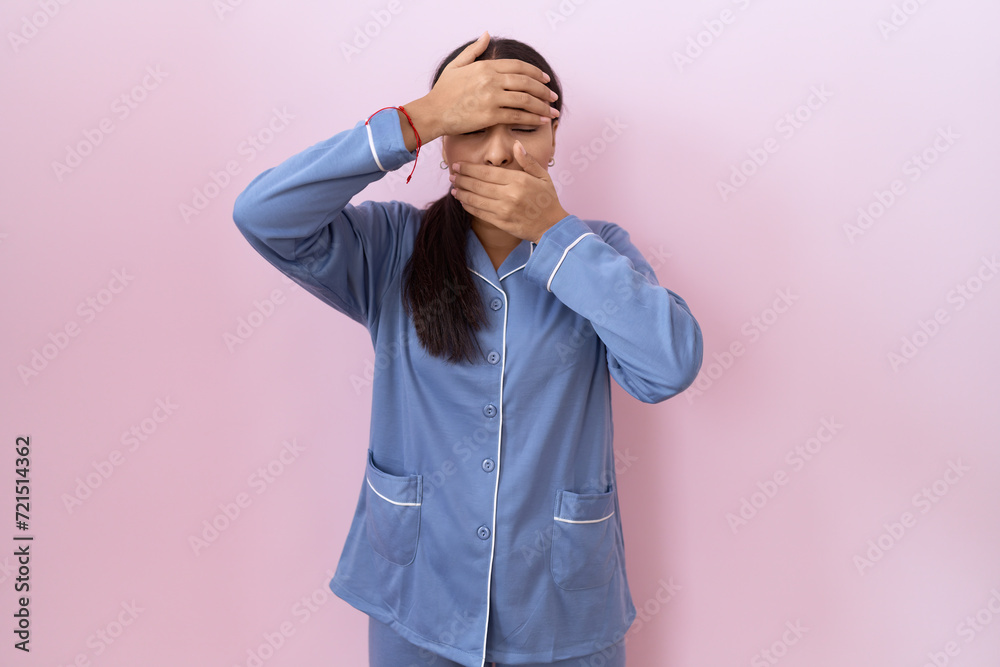 Young arab woman wearing blue pajama covering eyes and mouth with hands, surprised and shocked. hiding emotion Young arab woman wearing blue pajama covering eyes and mouth with hands, surprised and shocked. hiding emotion