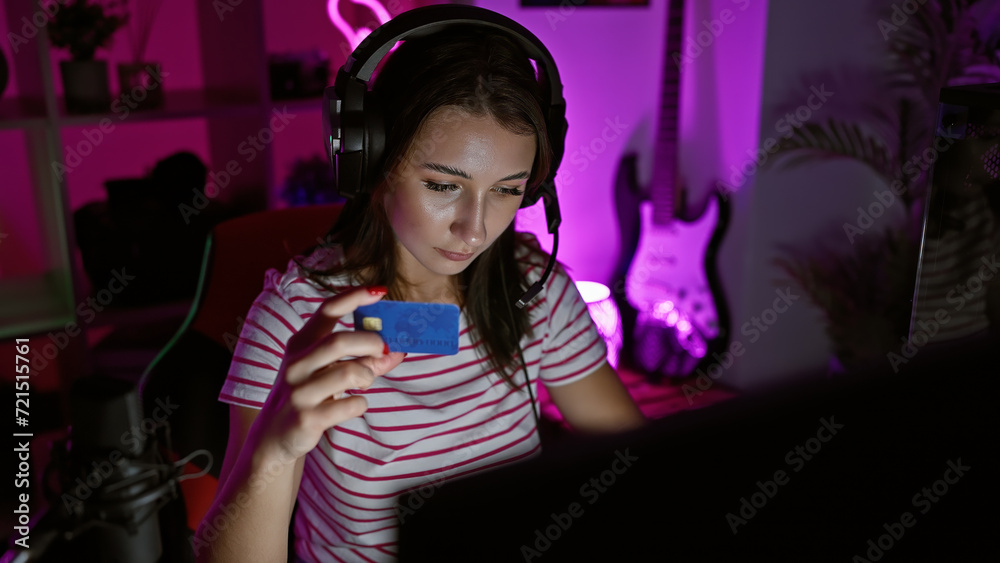 A young woman examines a credit card in a neon-lit gaming room at night