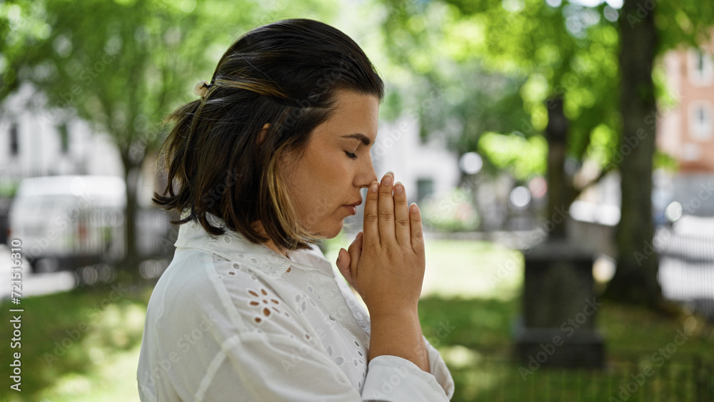 Beautiful young hispanic woman praying and mourning by tombstone at graveyard Beautiful young hispanic woman praying and mourning by tombstone at graveyard