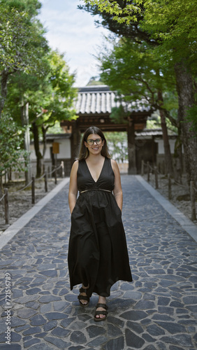 Cheerful, confident beautiful hispanic woman adorned with glasses standing tall, enjoying a walk, smiling radiantly for the camera at the zen ginkaku-ji temple garden in kyoto, japan.