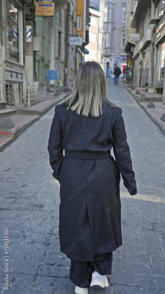 Back view of a young woman walking alone on a historic istanbul street, portraying urban exploration.
