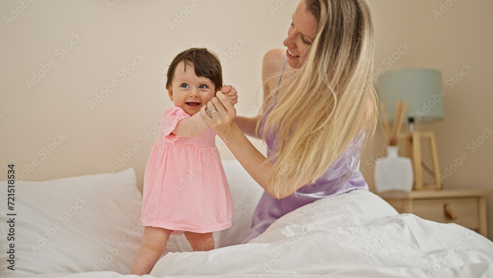Mother and daughter playing on bed dancing at bedroom