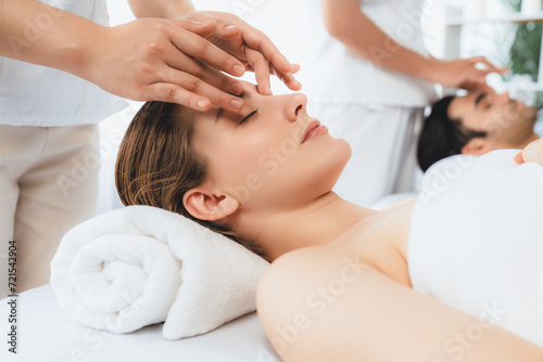 Caucasian couple enjoying relaxing anti-stress head massage and pampering facial beauty skin recreation leisure in dayspa modern light ambient at luxury resort or hotel spa salon. Quiescent photo
