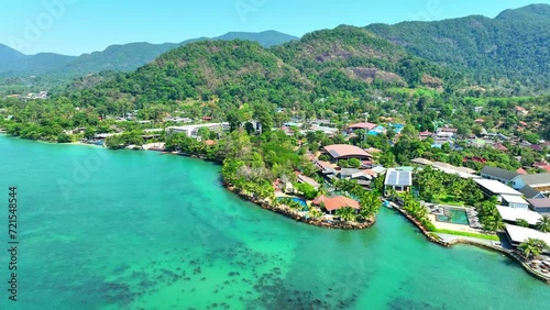 Pristine tropical coastline with azure waters, resorts dotting the shore, lush mountain forests, and a boundless blue sky. Ecotourism and biodiversity concept. Stock footage. Trat Province, Thailand.  photo