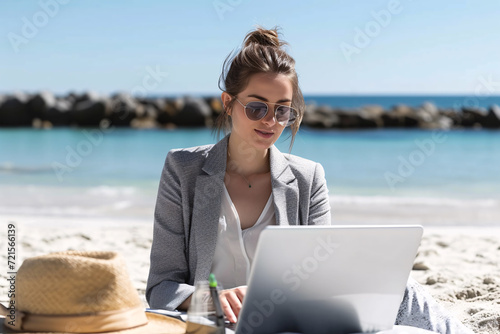 A businesswoman working on a laptop at the beach, concept of remote work