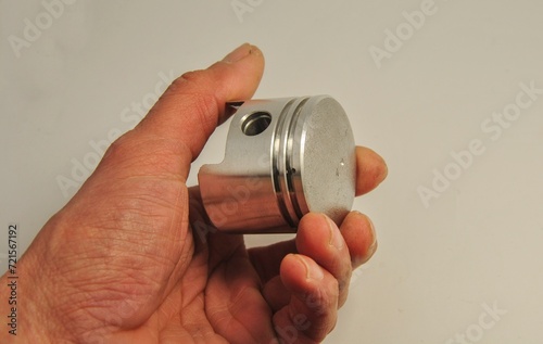 piston in hand on a light background. piston from a garden tool engine. repair of gasoline tools.