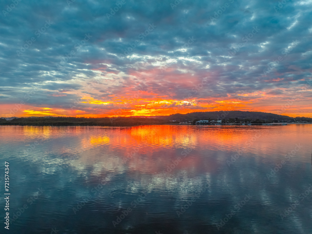 Naklejka premium Sunrise over the bay water with clouds and reflections